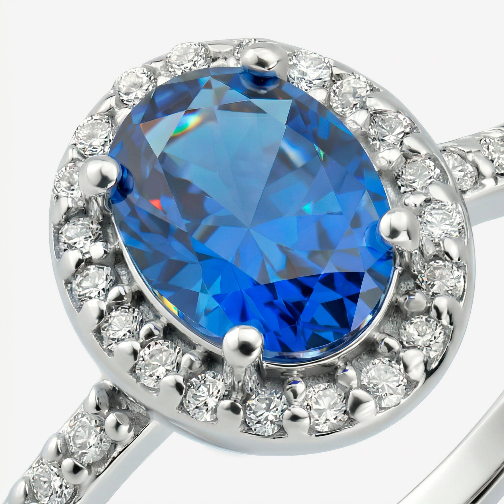 Detalhe da zircônia oval azul intenso com halo de zircônias brancas e aro cravejado do Anel Ivel em prata 925