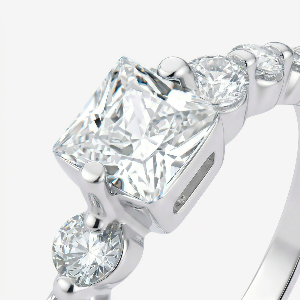 Detalhe da zircônia central de corte princess com quatro garras e zircônias redondas no aro do Anel Kael em prata 925