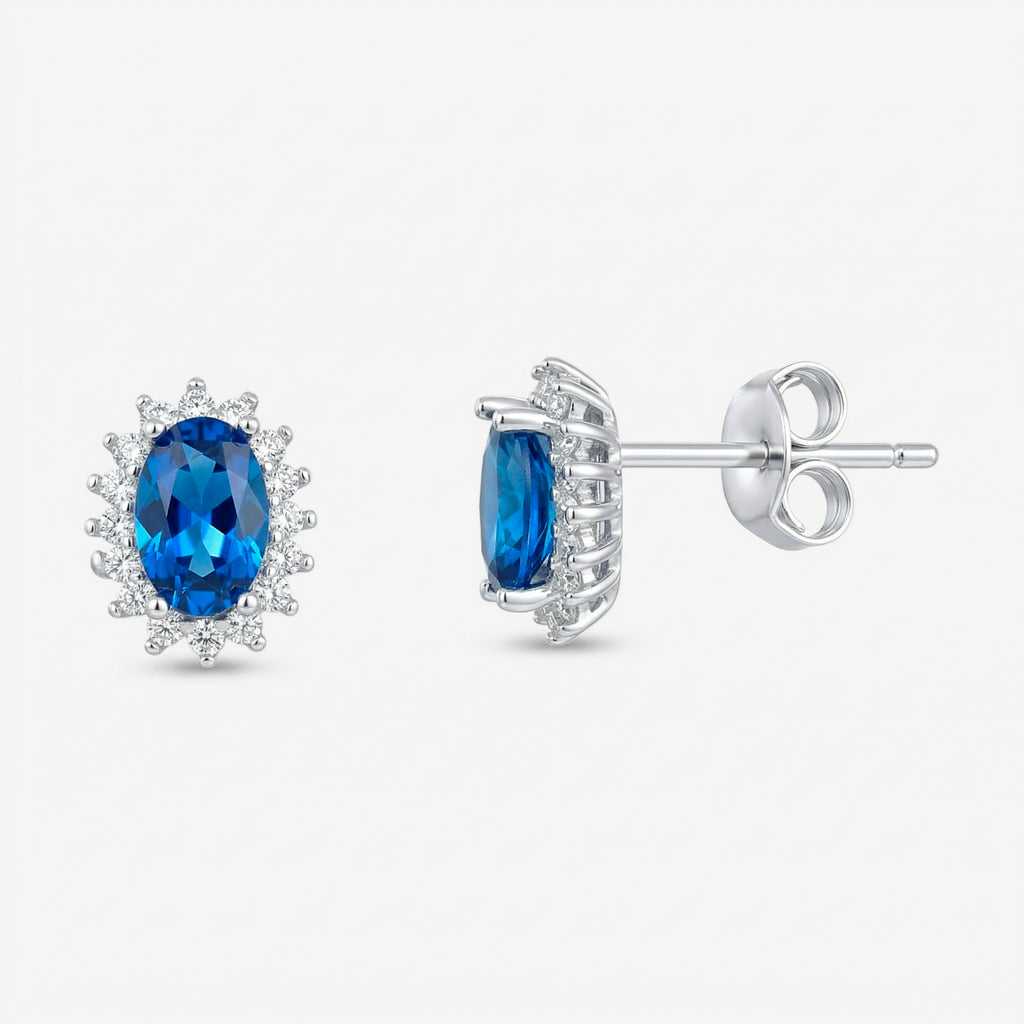 Par de brincos Avel em prata 925 com zircônia oval azul intenso em quatro garras e halo de zircônias brancas, vista frontal e lateral com fecho tarracha
